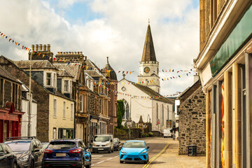 Obraz premium Scottish village street seen at midday in summer white chruch and clouds in background shot in Comrie, Perth and Kinross room for text