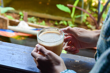 Close up of a hand holding a cup of latte coffee