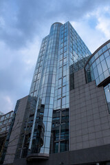 Glazed business building with cloud-covered sky. Concept: Business, economy, finance, architecture.