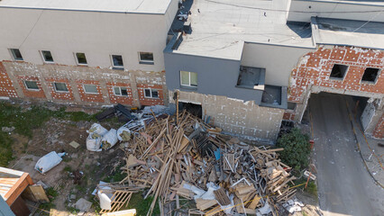 Drone photography of machinery dismantling a house and removing ruble during sunny summer day.