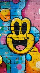 Vibrant graffiti of a smiling yellow face on a brick wall, with colorful splashes and patterns. The artwork exudes a cheerful and playful vibe, adding a lively touch to the urban environment.