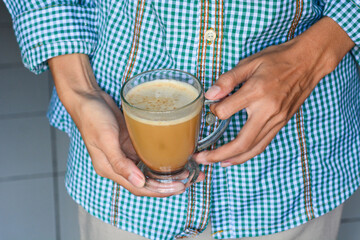 Close up of a hand holding a cup of latte coffee