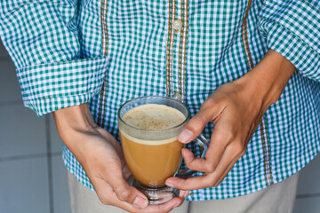Close up of a hand holding a cup of latte coffee