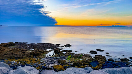 Scenic view of the Atlantic Ocean during sunset, Iceland, Keflavik. Calm ocean, low tide near the rocky shore in summer in Iceland.