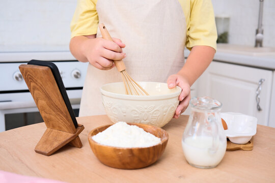 A child enthusiastically baking in a cozy kitchen filled with various delicious ingredients