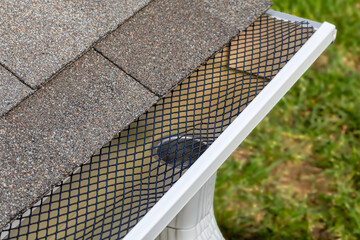 Installing gutter guard mesh screen on rain guttering. Home maintenance, yardwork and roof damage concept