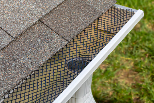 Installing gutter guard mesh screen on rain guttering. Home maintenance, yardwork and roof damage concept