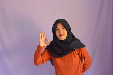 Beautiful young student girl wearing orange student t-shirt smiling happily pointing with hand and finger to the side on isolated purple background