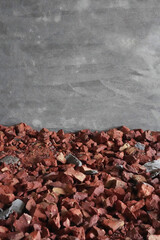 A grey concrete wall and red broken bricks on the floor. Base for pouring the floor with concrete. Vertical photo. Space for text. Industrial backdrop. Construction of a house.