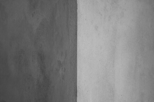 Grey concrete wall corner background. Light and dark sides. Shadow on grey background. Industrial backdrop for design. Close-up, horizontal photo, selective focus.