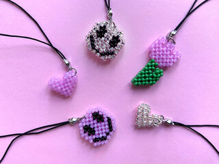 Beaded cell phone charms over a pink paper textured background. Flower smile and heart shaped...