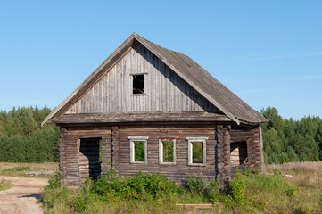 Old abandoned rough log house at forest edge in northern Russia