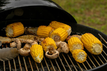 Grilled corn and mushrooms on a barbecue, perfect for summer cookouts and outdoor gatherings