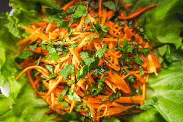 Carrot salad with parsley, dressed with traditional French vinaigrette sauce, on lettuce. Close-up