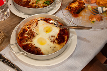 Traditional shakshuka Middle Eastern breakfast of poached eggs and chunky tomato sauce and garlic.