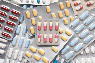 Antibiotic pills in blisters as background, top view