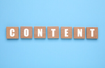 Word Content made of wooden cubes with letters on light blue background, top view