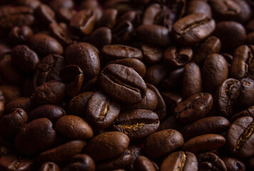 Naklejka premium Brown Roasted Coffee Beans Closeup On blurred Background of coffee beans. Top view of backdrop of dark brown coffee beans. Coffee Beans texture.