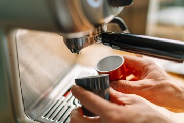 Close-up of a person preparing espresso with a coffee machine in a cozy kitchen setting.