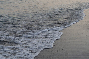 Gentle waves lap the shore at dusk on a tranquil beach in Málaga, Spain. Perfect for themes of relaxation, coastal serenity, and nature's beauty.