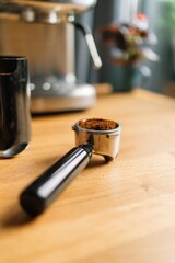 Close-up of a portafilter being filled with ground coffee on a wooden table