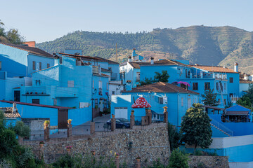 A picturesque view of Júzcar, the blue-painted village in Andalusia, Spain, bathed in morning sunlight. Perfect for travel brochures, cultural features, or serene landscape themes. © Outsiderzone