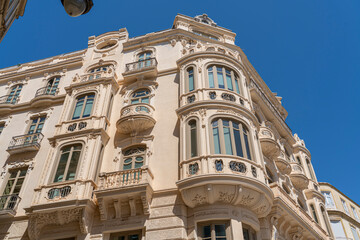 A charming facade in Málaga, Spain, featuring traditional balconies with shuttered windows and flower pots. Perfect for illustrating Spanish architecture, culture, and urban aesthetics - Powered by Adobe