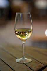A close-up shot of a white wine glass on a wooden table, capturing the reflection of an outdoor setting. Perfect for themes of leisure, dining, and elegant lifestyle