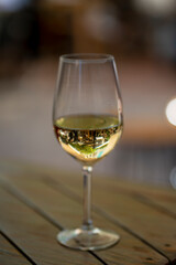 A close-up shot of a white wine glass on a wooden table, capturing the reflection of an outdoor setting. Perfect for themes of leisure, dining, and elegant lifestyle