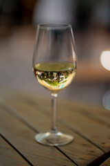 A close-up shot of a white wine glass on a wooden table, capturing the reflection of an outdoor setting. Perfect for themes of leisure, dining, and elegant lifestyle