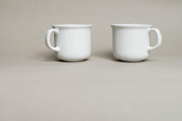 White porcelain mugs on grey paper background.