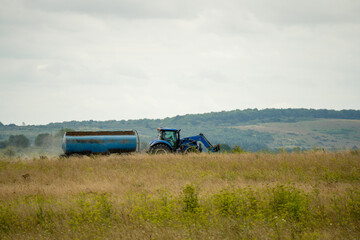 Fototapeta premium large blue New Hollnad T5 tractor towing a 30,000 litre water tanker in countryside
