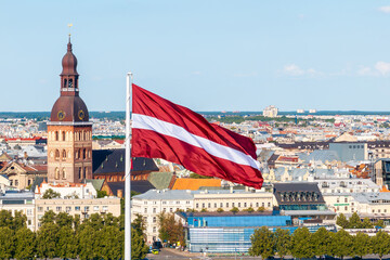Latvian national flag waving with Riga cityscape in the background