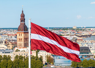 Latvian national flag waving with Riga cityscape in the background