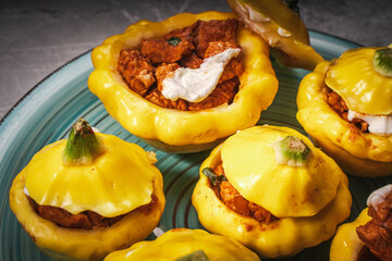 Turkey baked in pumpkin with cheese. A few stuffed pumpkins on a turquoise plate. Close-up.