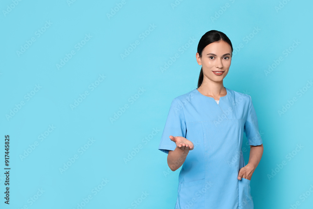 Wall mural smiling nurse holding something on light blue background. space for text