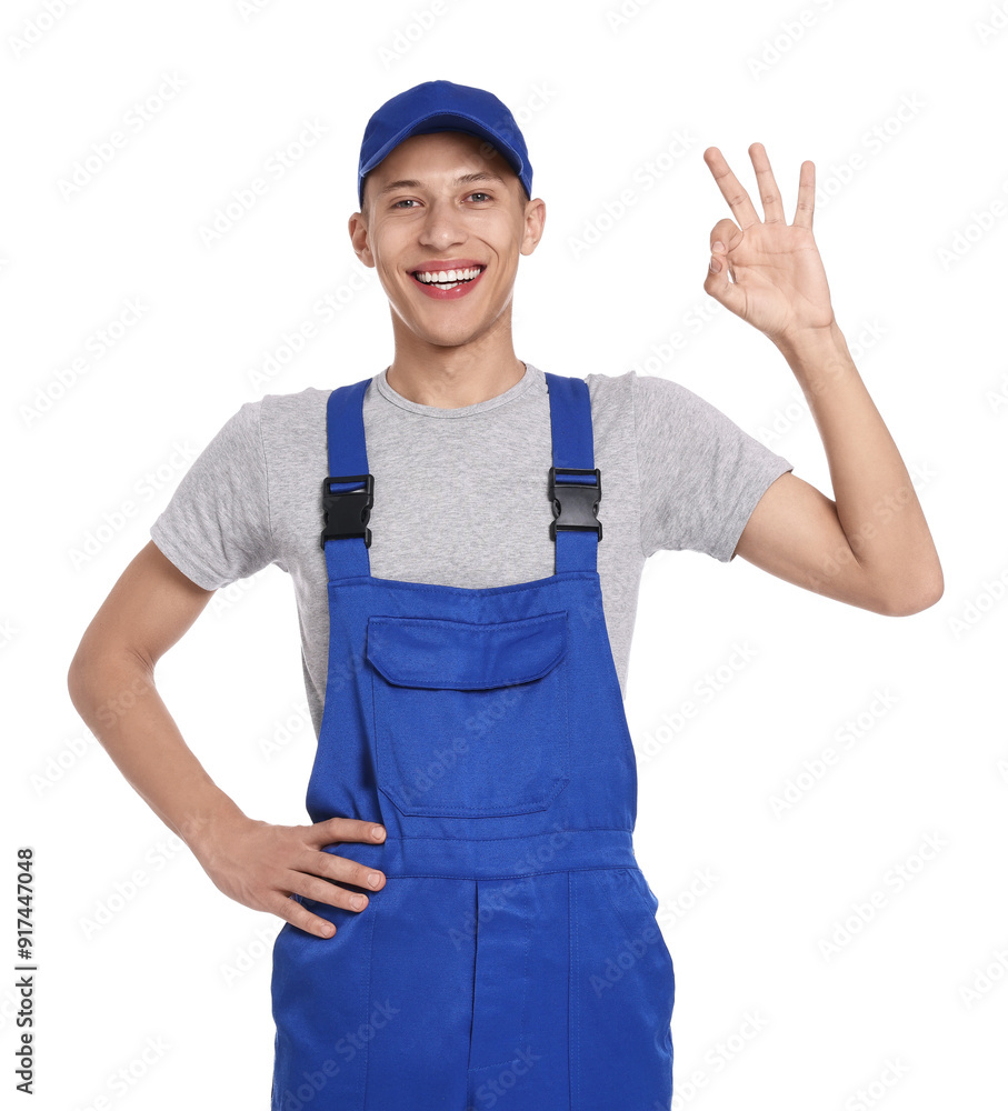 Wall mural Smiling auto mechanic showing ok gesture on white background