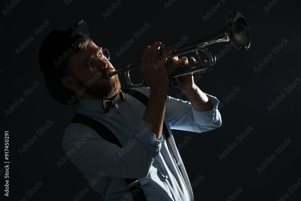 Wall mural Professional musician playing trumpet on black background