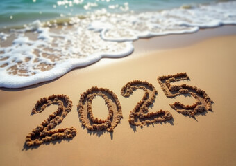 2025 written in the sand on a beach with a wave coming in the background.