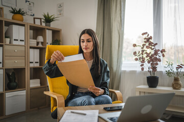 Adult woman work from home, open and read a letter from envelope