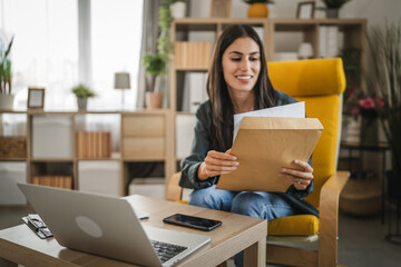 Adult woman work from home read a letter post document from envelope