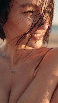 Close up portrait of beautiful brunette woman smiling on the beach during a golden sunset