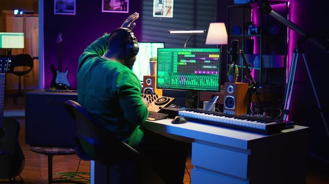 Sound engineer mixing and mastering new music on console and daw software in home studio, twisting pre amp knobs. Talented composer producing songs for the industry. Camera B.