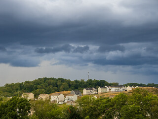 Dramatic thunderstorm clouds hanging over a US residential neighborhood with bright gap in the sky on a summer evening.