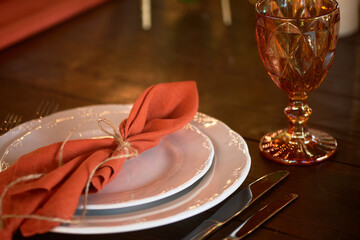 Table setting with orange napkins and glasses. Classic. Warm shades.
