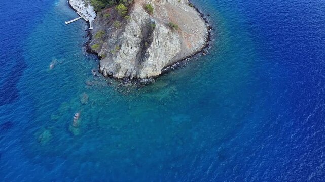 4k drone image of a peninsula made up of rocks surrounded by sea, with the inside of the sea, that is, the part of the peninsula that is under the sea, also visible, panning from above to the right