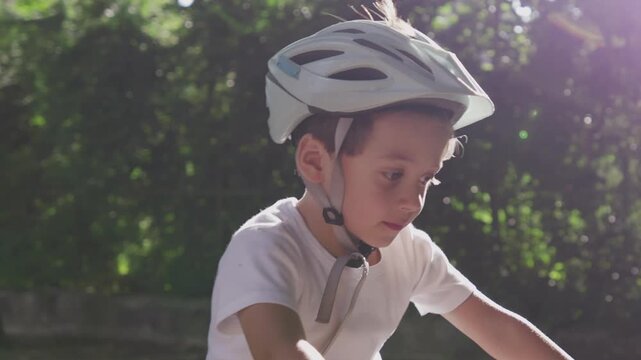 Young boy with a helmet riding a bicycle in a park, stopping to enjoy the moment, highlighting outdoor fun and the freedom of childhood adventures in a natural setting