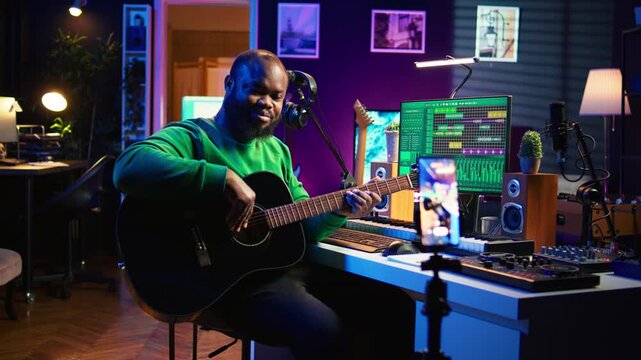 Guitarist instructor hosting guitar lessons online using a mobile phone, recording tutorial for master class. Artist musician explains acoustic instrument accords, assistance for beginners. Camera B.