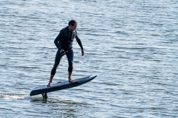 Man riding electric hydrofoil surfboard over rippling water