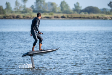 A man glides effortlessly on an electric hydrofoil surfboard